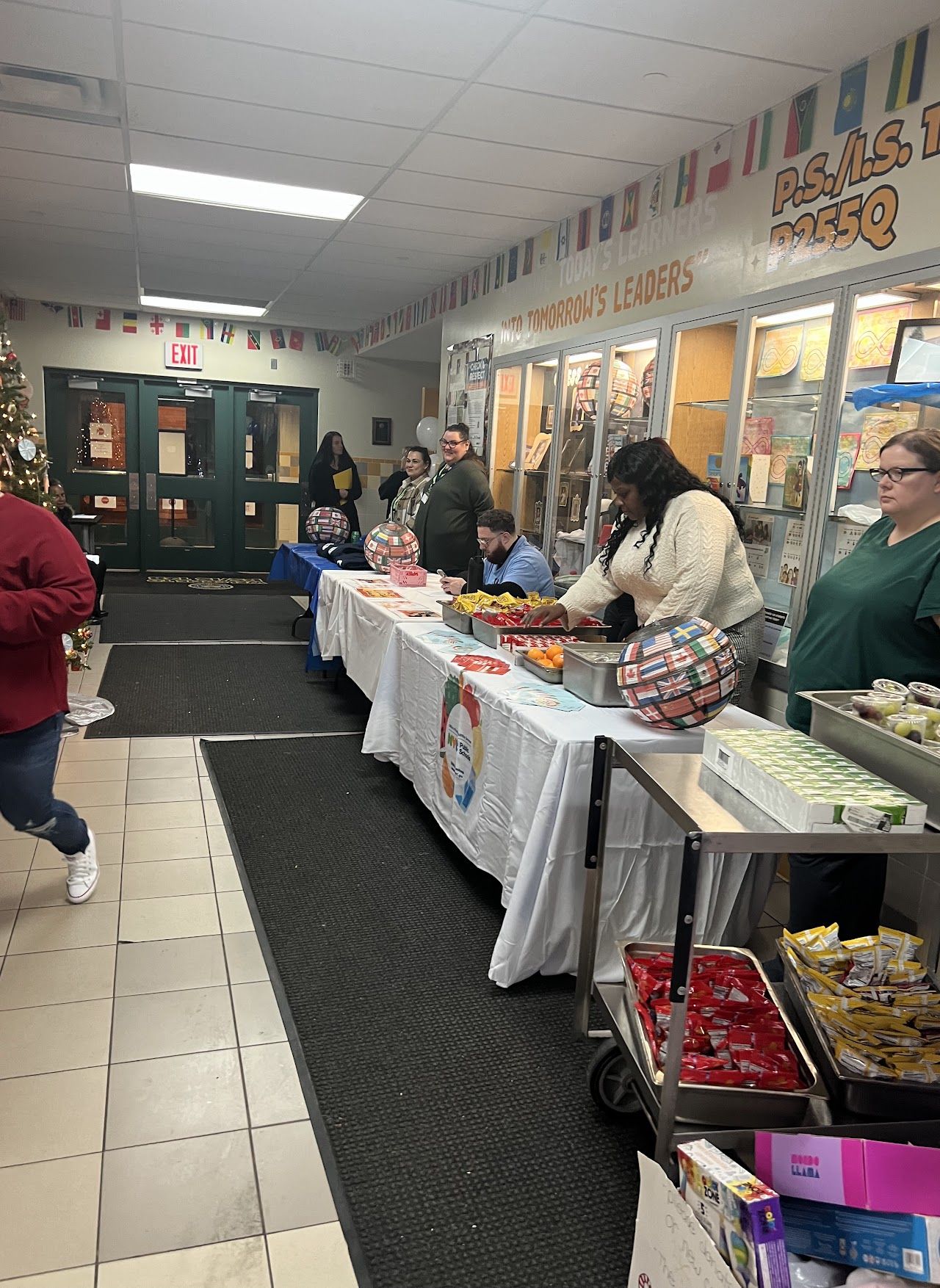 Families walk down a hallway lined with information tables and display cases.